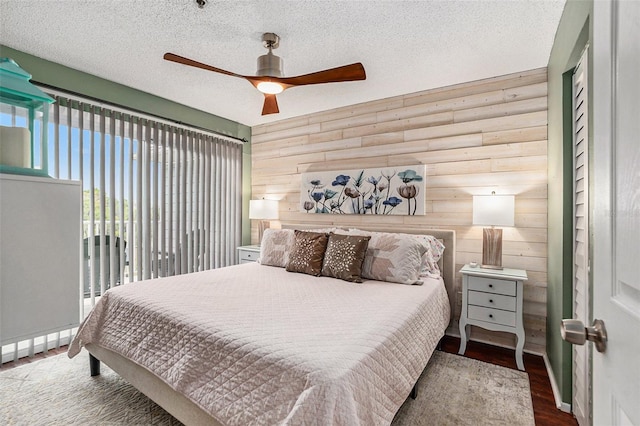 bedroom with ceiling fan, log walls, hardwood / wood-style floors, a textured ceiling, and wooden walls