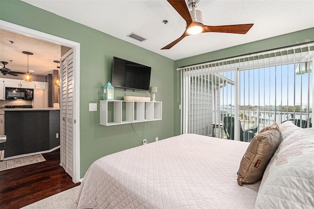 bedroom featuring ceiling fan, access to exterior, a textured ceiling, and hardwood / wood-style flooring