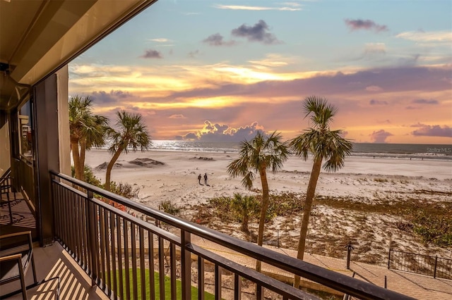 balcony at dusk with a water view and a beach view