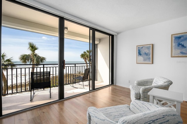 interior space with wood-type flooring, floor to ceiling windows, a textured ceiling, and a water view