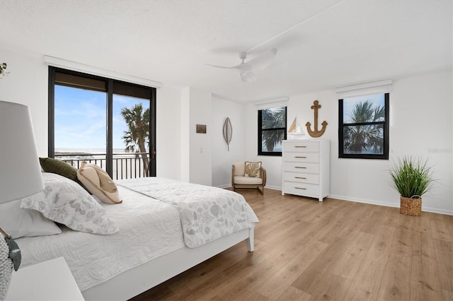 bedroom featuring expansive windows, light wood-type flooring, access to outside, and ceiling fan