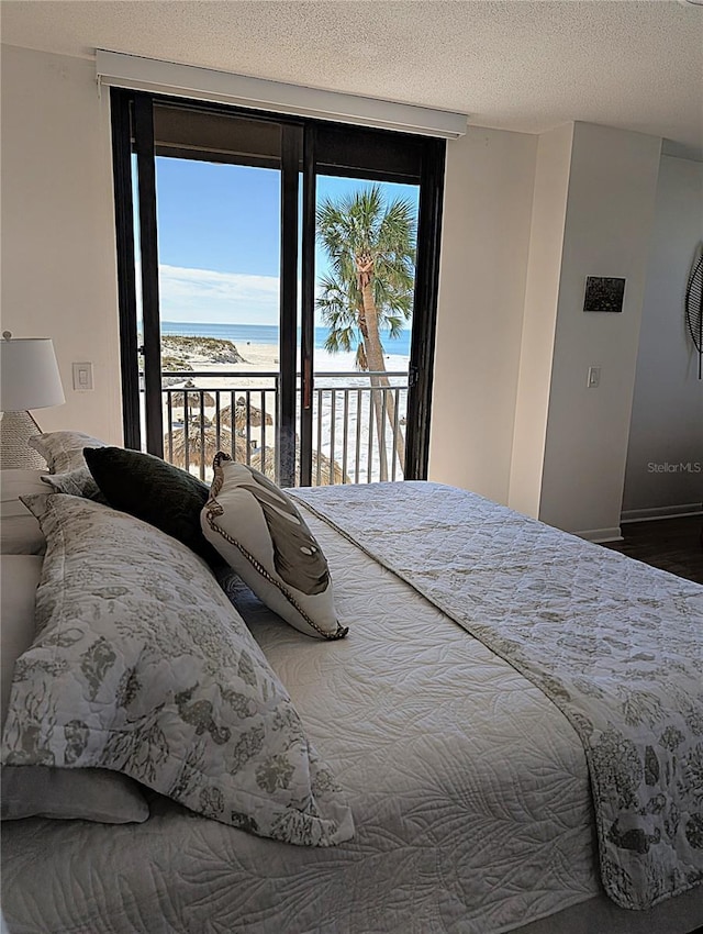 bedroom featuring access to outside, a textured ceiling, and a water view