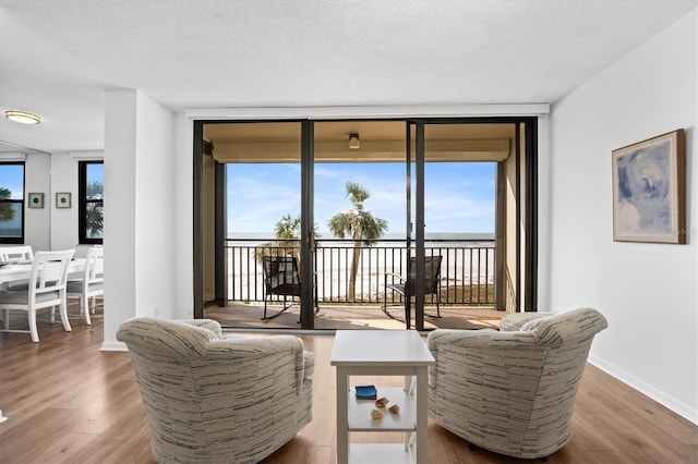 living room featuring hardwood / wood-style flooring, a textured ceiling, and a wall of windows