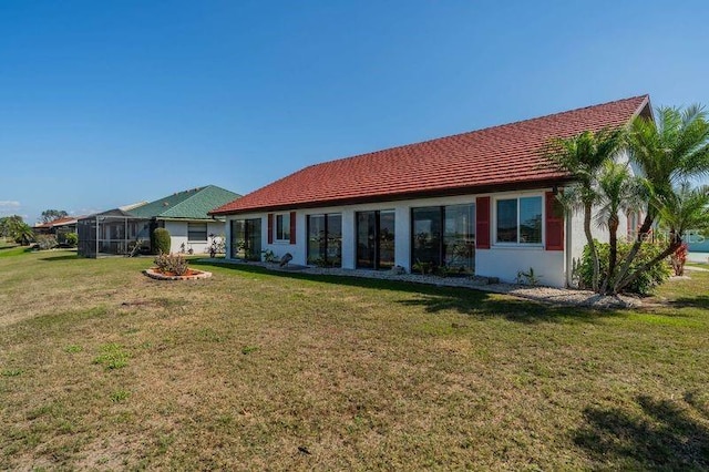 rear view of house with a lawn and glass enclosure