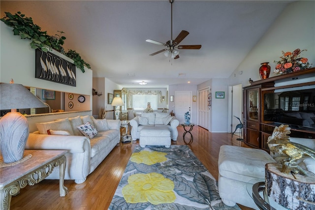 living room with hardwood / wood-style flooring, ceiling fan, and vaulted ceiling