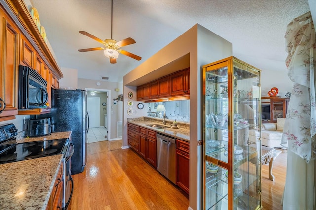 kitchen featuring black appliances, sink, light hardwood / wood-style floors, light stone counters, and a textured ceiling