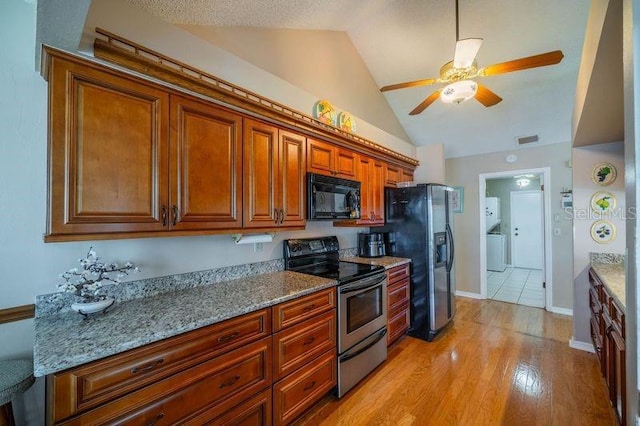 kitchen featuring stainless steel appliances, lofted ceiling, light stone counters, and light hardwood / wood-style floors