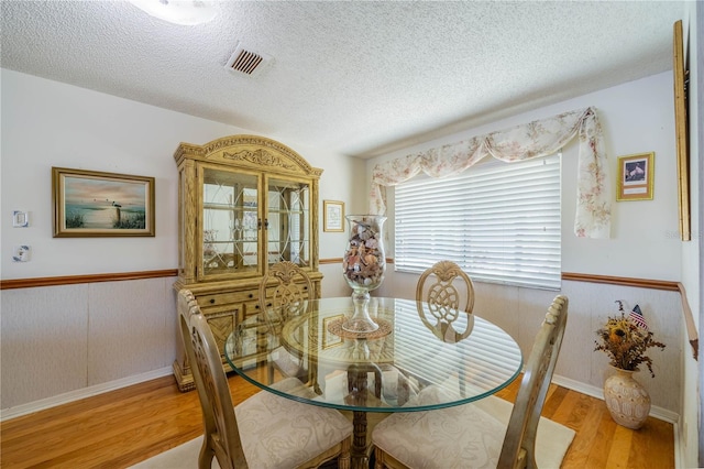 dining area featuring light hardwood / wood-style floors and a textured ceiling