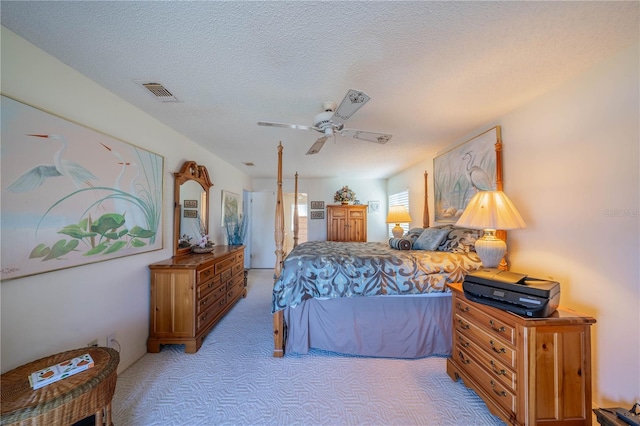 bedroom featuring ceiling fan, light colored carpet, and a textured ceiling