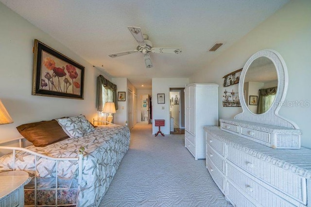 carpeted bedroom with ceiling fan and a textured ceiling