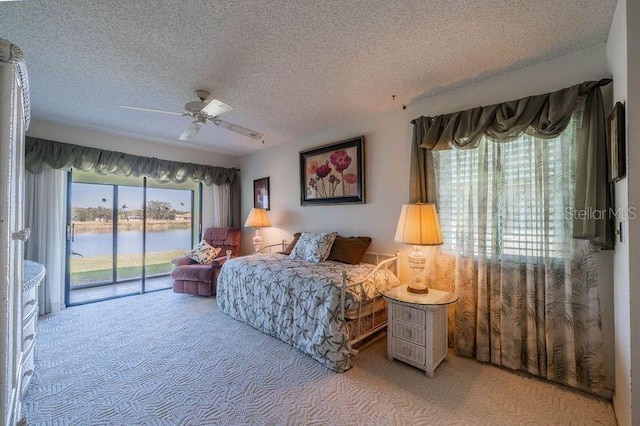 carpeted bedroom with a textured ceiling, access to outside, ceiling fan, and a water view