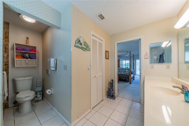 bathroom featuring tile patterned flooring, vanity, a textured ceiling, and toilet