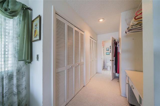 hallway with light colored carpet and a textured ceiling