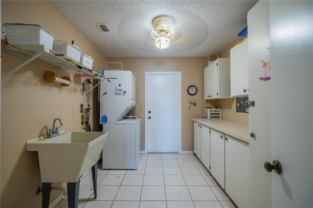 washroom with sink, cabinets, a textured ceiling, light tile patterned floors, and stacked washer / dryer