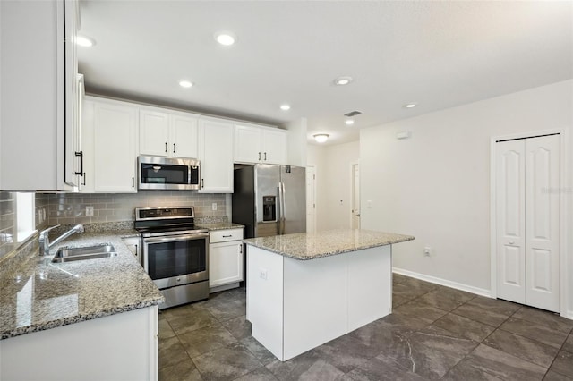 kitchen with stainless steel appliances, sink, white cabinets, and a center island