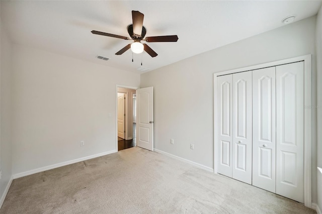 unfurnished bedroom featuring ceiling fan, light colored carpet, and a closet