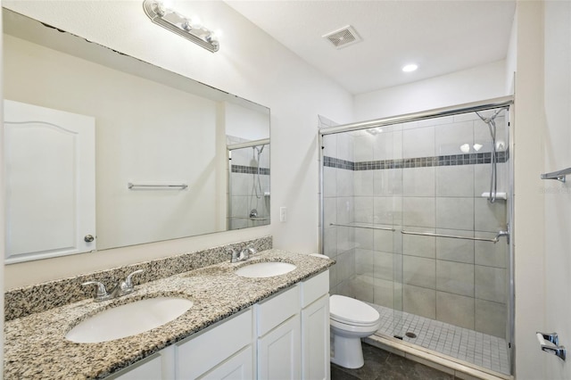 bathroom with toilet, vanity, and a shower with door