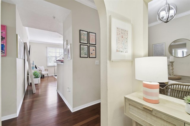 corridor featuring an inviting chandelier, ornamental molding, and dark hardwood / wood-style flooring