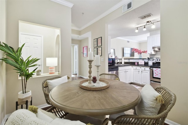 dining space with sink and ornamental molding