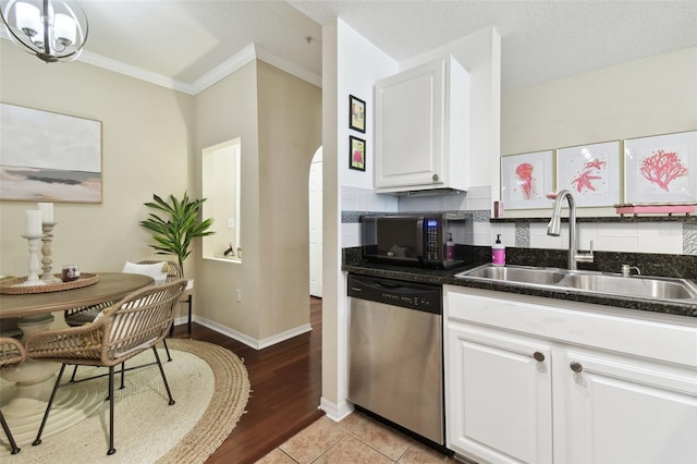 kitchen with crown molding, white cabinetry, light tile patterned floors, stainless steel dishwasher, and sink