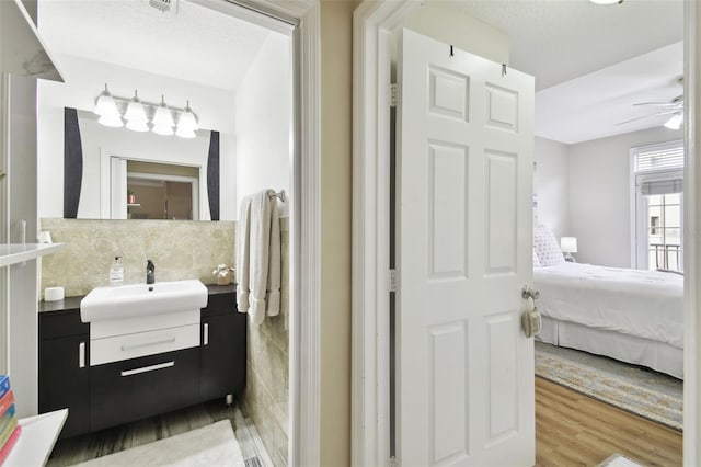 bathroom featuring vanity, hardwood / wood-style flooring, ceiling fan, and backsplash