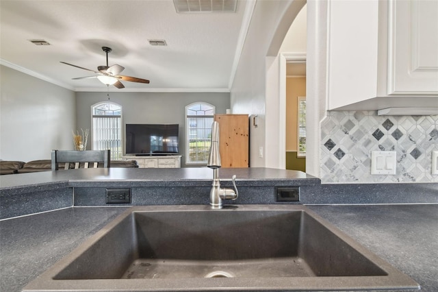 kitchen featuring white cabinetry, ceiling fan, backsplash, crown molding, and sink