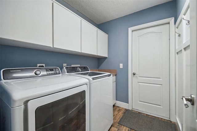 laundry room with dark wood-type flooring, cabinets, washer and dryer, and a textured ceiling