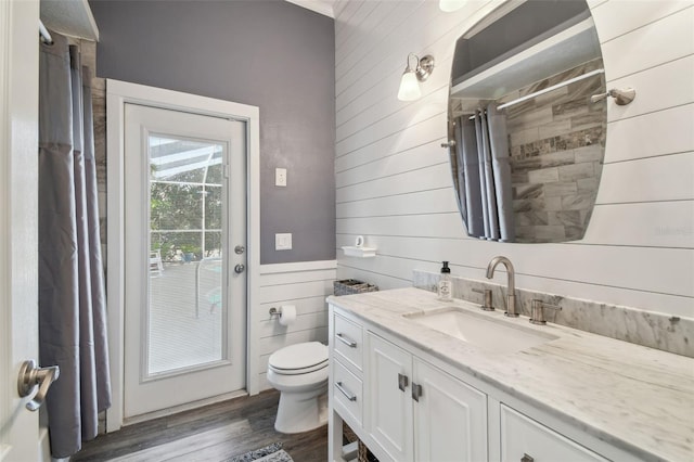 bathroom featuring wood-type flooring, vanity, a shower with curtain, wooden walls, and toilet