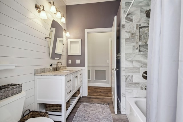 full bathroom featuring hardwood / wood-style floors, tiled shower / bath, vanity, toilet, and crown molding