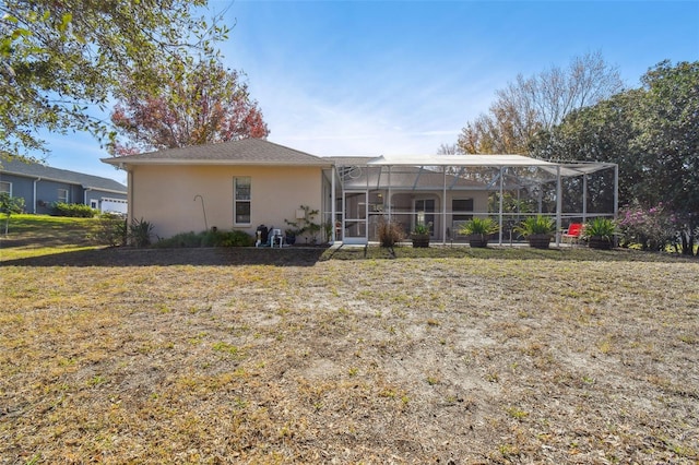 back of property with glass enclosure and a yard