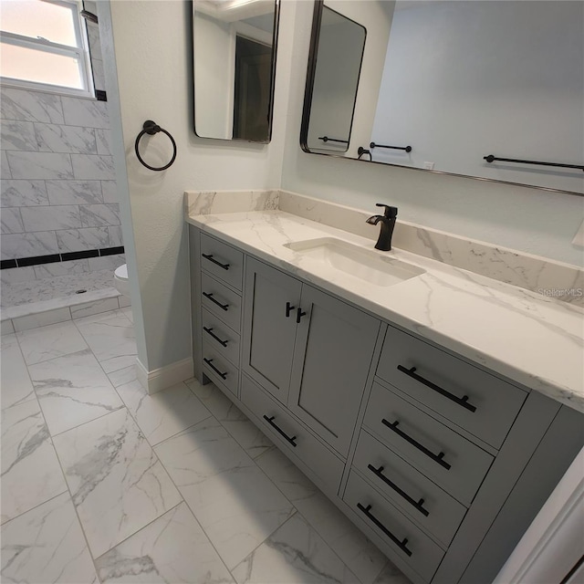 bathroom featuring tiled shower, vanity, and toilet