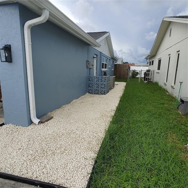 view of side of home featuring cooling unit and a lawn