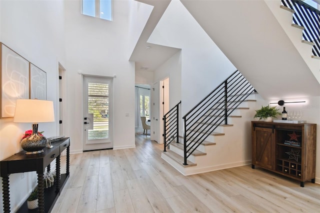 entrance foyer with a towering ceiling and light wood-type flooring