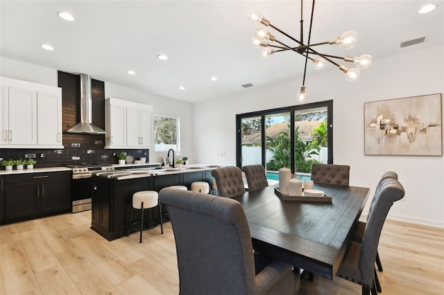 dining room with a chandelier, sink, and light hardwood / wood-style flooring