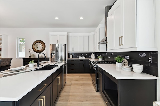 kitchen with dishwashing machine, black gas stove, a kitchen island with sink, white cabinetry, and stainless steel refrigerator with ice dispenser