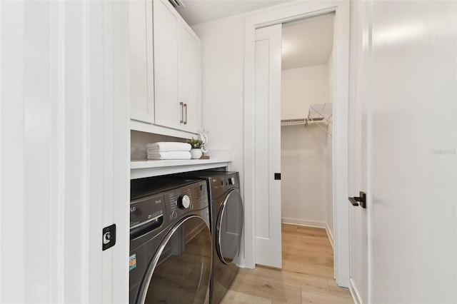 clothes washing area with cabinets, independent washer and dryer, and light hardwood / wood-style floors