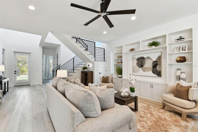 living room with built in features, ceiling fan, and light hardwood / wood-style flooring