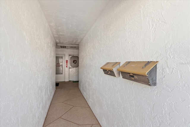 hallway with tile patterned floors and a textured ceiling