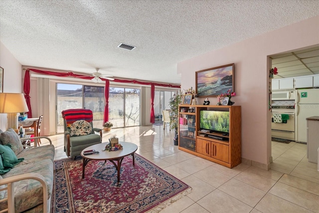 living room with ceiling fan, light tile patterned floors, and a textured ceiling