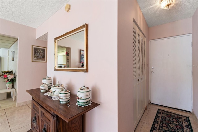 hall featuring light tile patterned flooring and a textured ceiling