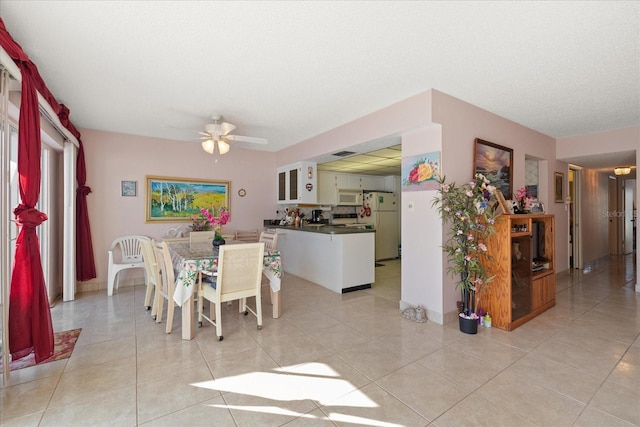 tiled dining room with a textured ceiling and ceiling fan