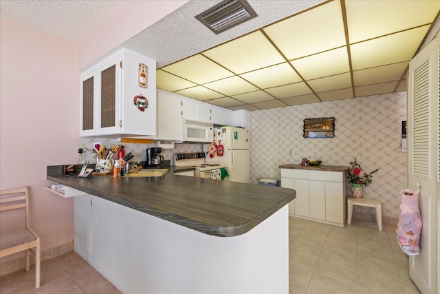 kitchen with white cabinetry, white appliances, kitchen peninsula, and light tile patterned flooring