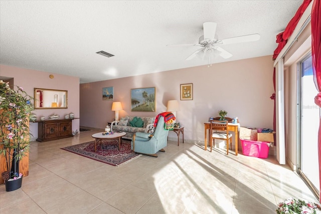 tiled living room with ceiling fan and a textured ceiling