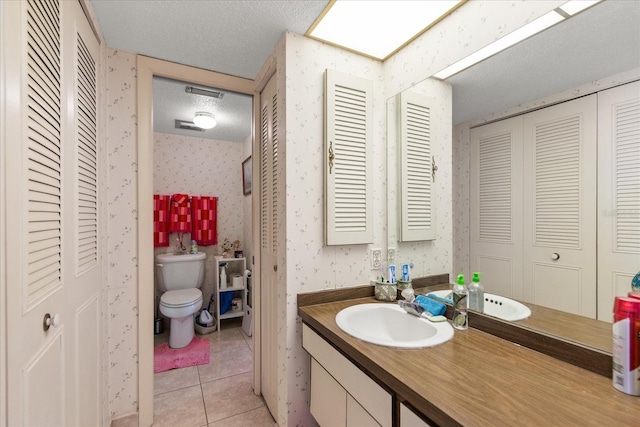 bathroom featuring vanity, tile patterned floors, toilet, and a textured ceiling