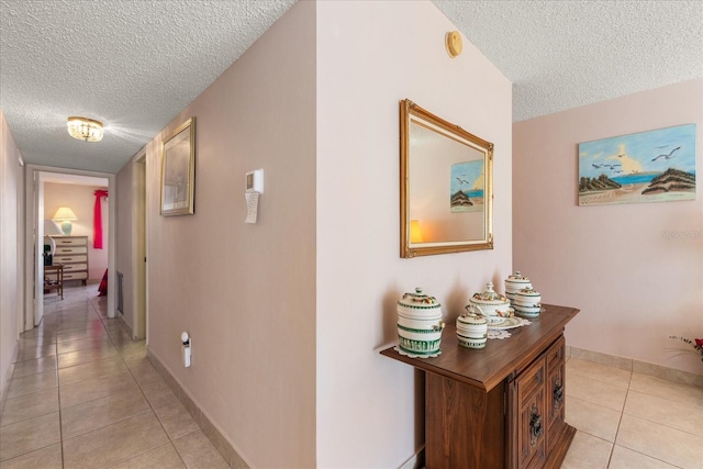 hallway featuring a textured ceiling and light tile patterned floors