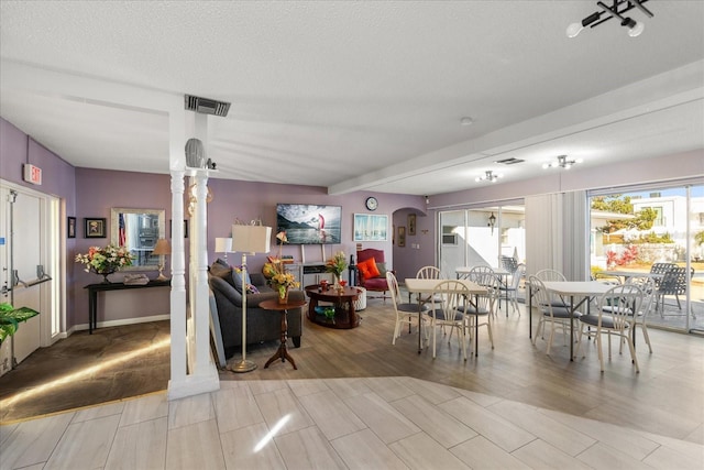 dining room with ornate columns and a textured ceiling