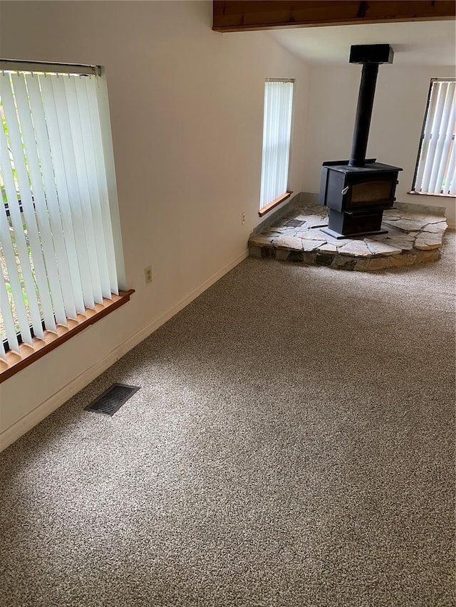 unfurnished living room with carpet flooring and a wood stove