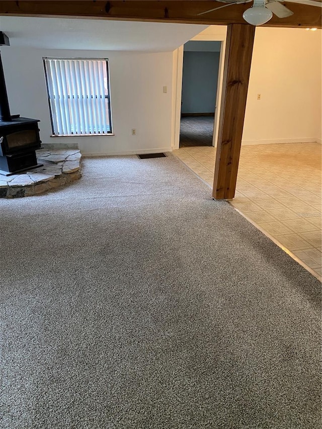 carpeted empty room featuring a wood stove