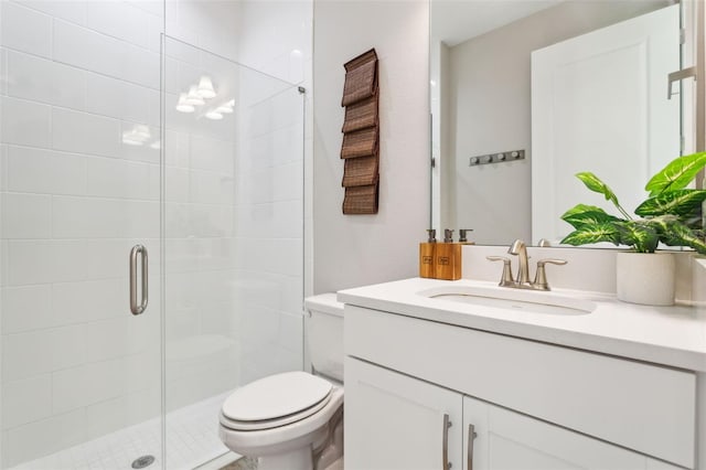 bathroom featuring toilet, a shower with shower door, and vanity