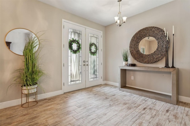 foyer entrance with french doors, an inviting chandelier, and light hardwood / wood-style floors